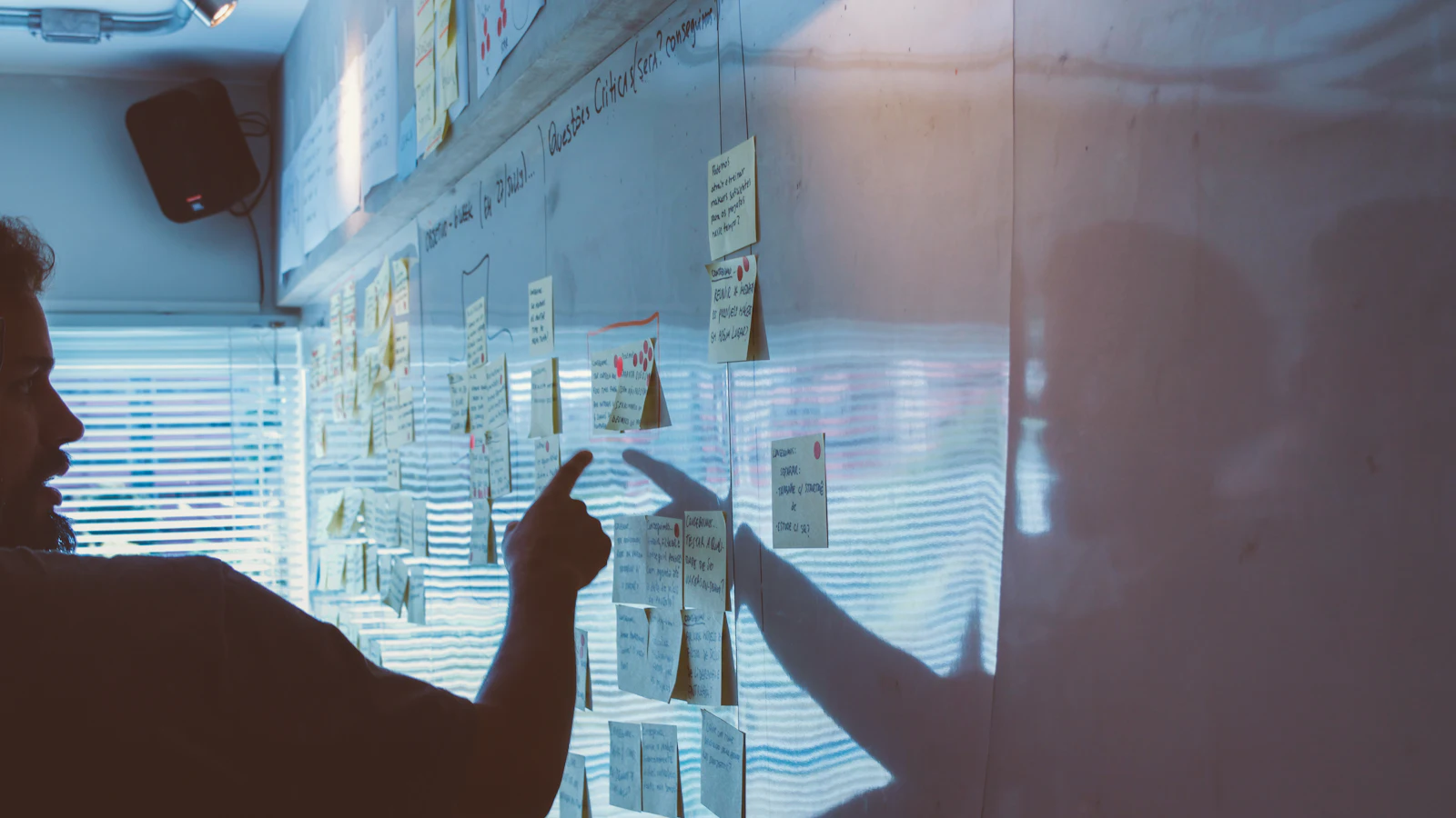 Person pointing at plans pinned to a wall