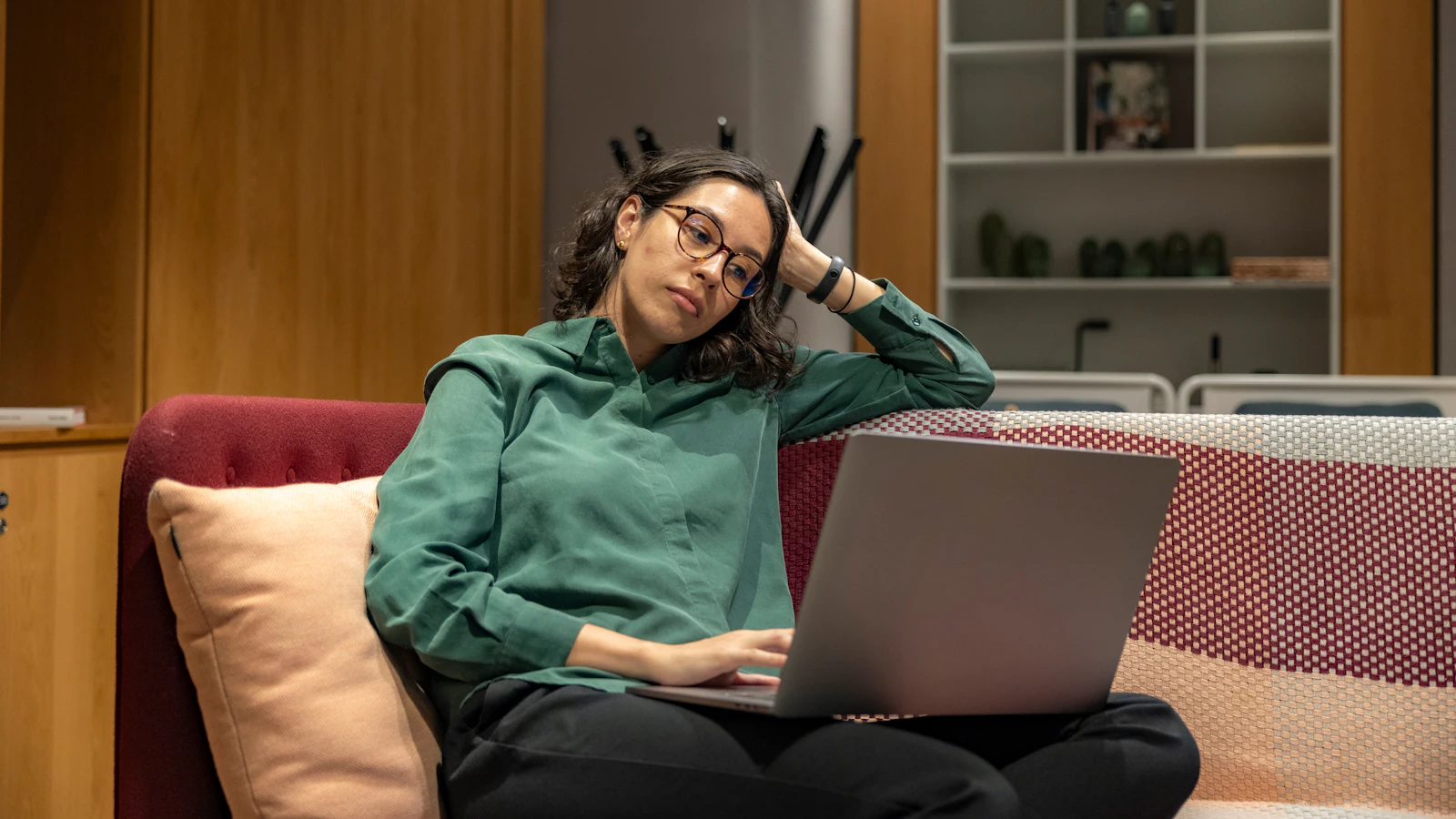Woman on a sofa looking frustrated at her laptop